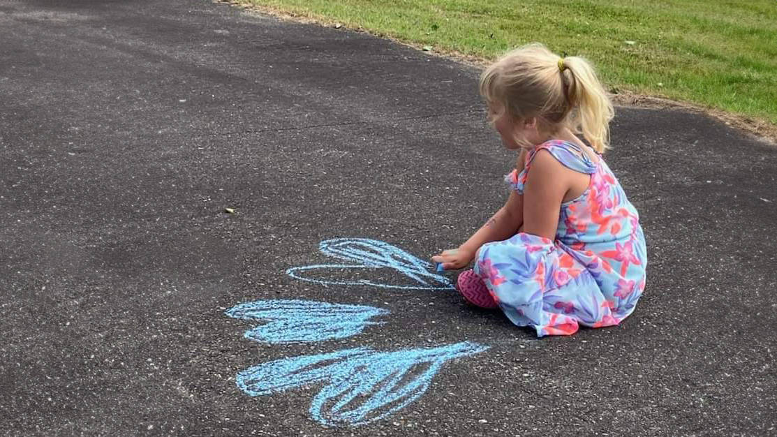 little girl drawing with chalk